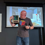 James (Bald Engineer) at Supercon 2023 on stage presenting Mega IIe